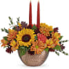This stunning centerpiece features medium yellow sunflowers, orange carnations, bronze daisy spray