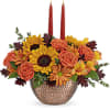 This stunning centerpiece features medium yellow sunflowers, orange carnations, bronze daisy spray