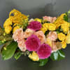 This floral design has a mix of roses arranged with seasonal flowers.