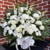 An all-white funeral basket featuring  lilies, roses, dragon snaps, and more