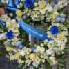 An open round wreath that can include  white lilies,white mums, white