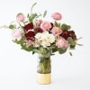 Roses, Ranunculus and more are designed in a glass cylinder vase.