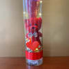 A red Valentine&#039;s Day plush bear with pink paper rose carefully arranged