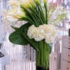 Sculptural calla lilies with white hydrangeas and orchids in a large glass