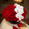 This arrangement is in a modern black ceramic vase with sixty red