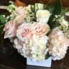 Soft pink and white roses arranged with hydrangea, wax flower and greenery