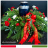 A simple urn surround, filled with lush evergreens, carnations, and berries. A
