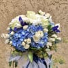 Beautiful blue and white arrangment featuring hydrangeas, iris, roses, daisies, and green