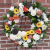 An uplifting, colorful Sympathy Wreath with seasonal flowers and greens.