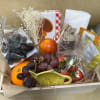 A gift basket filled with seasonal fresh fruits, cheese, crackers, honey, sweet