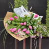 Dozen of seasonal tulips wrapped with eucalyptus and other greens tide with