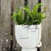 This handmade Indonesian planter sports half a face in tone-on-tone white. 