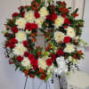 Red and white circular funeral spray with chrysanthemums, roses, snapdragons, and other