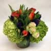 This short arrangement comes complete with green hydrangea, orange tulips, blue hyacinth
