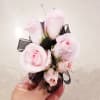 Corsage made with light pink spray roses, black sheer ribbon and rhinestones