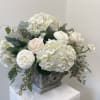 A substantial arrangement of white and cream Flowers set with local greenery