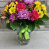 A colorful mix of daisies, alstroemeria, carnations and aster in a clear