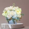 Soft roses, hydrangea, orchids, and eucalyptus in a ceramic vase make a