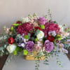 An arrangement includes hydrangeas, roses, ranunculus, stock, alstroemeria, and foliage in a