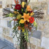 A grapevine cross on a standing easel swathed with orange lilies, red