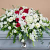 A funeral casket spray consisting of snapdragons, gladiolas, roses, buttons, carnations, hydrangeas