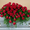 A beautiful red rose casket spray with a variety of greens.