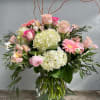 A vase arrangement in a posie vase.  White hydrangea, pink ohara