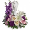 A keepsake angel statue surrounded by soft colored flowers.