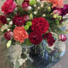 Red and red-tinged roses with red and salmon-colored carnations among white Lisianthus