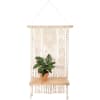 A wooden shelf featuring a cotton macram&eacute; designed backdrop leading to shelf