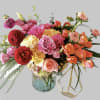 A clear cylinde vase of colorful roses and seasonal blooms brightens and