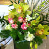 Beautiful, long-lasting cymbidium orchids are arranged with roses, dendrobiums, ti leaves and