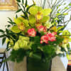 Beautiful, long-lasting cymbidium orchids are arranged with roses, dendrobiums, ti leaves and