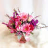 In a pink mason jar, a mixture of all pink flowers including