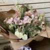 White and blush flowers wrapped in brown paper.