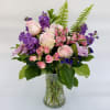 A bouquet of purple and pink blooms in a clear glass vase