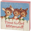 A wooden block sign displaying vintage art of three cute reindeer in