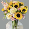 This arrangement includes  sunflowers ,roses and seasonal blooms It is the