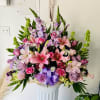 A beautiful arrangement of lavender and pink blooms including roses, lilies, gladioli