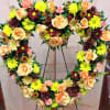 This beautiful rust, butterscotch, and yellow heart-shaped floral arrangement on an easel