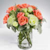 This arrangement includes peach roses, white roses, white spray roses, orange carnations
