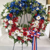 A fresh cut flower wreath adorned with red, white and blue flowers.