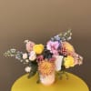 A fresh flower arrangement in hues of yellow, pink, and blue. Flowers