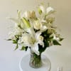An elegant arrangement of white roses, lilies, alstroemeria, and greenery in a