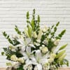 All white floral display with lilies, lisianthus, roses, bells of ireland, stock