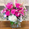 Vibrant pink and purple flowers in a 6.5&rdquo; clear glass vase.