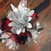 Red roses tipped with black paint and silver daisies are accented with