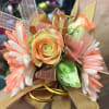 A wrist corsage with coral tipped flowers and accented with white rose