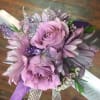 Lavender roses and daisies surrounded by white wax, purple and lavender ribbon