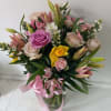 Beautifully lined pink/yellow mix of roses and spring flowers in a vase